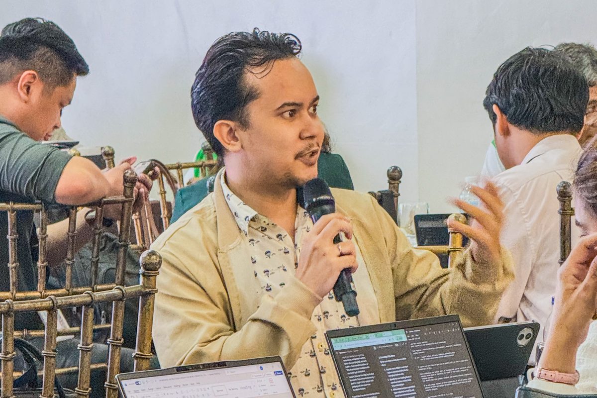A micro-credential author speaking into a microphone, laptop open, during the build session