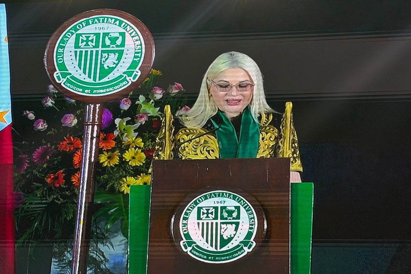 Dr. Ingrid Ursua delivering the commencement address from the podium at Our Lady of Fatima University